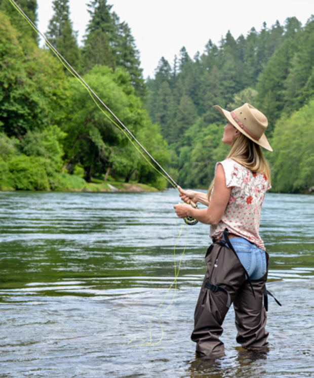 A woman fly fishing in a shallow river