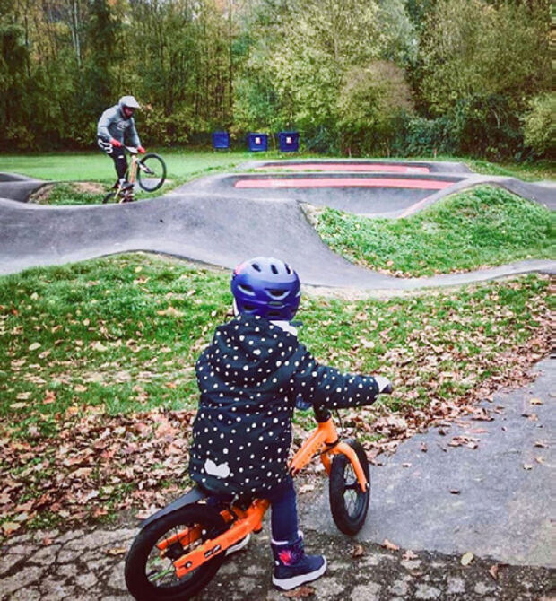 A small child on a balance bike at a neighborhood pump track