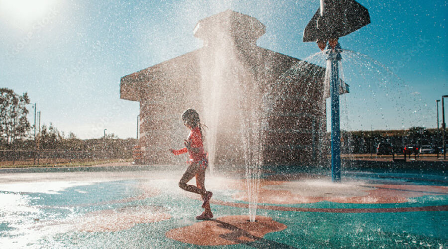 A child running through a splash pad on a hot afternoon