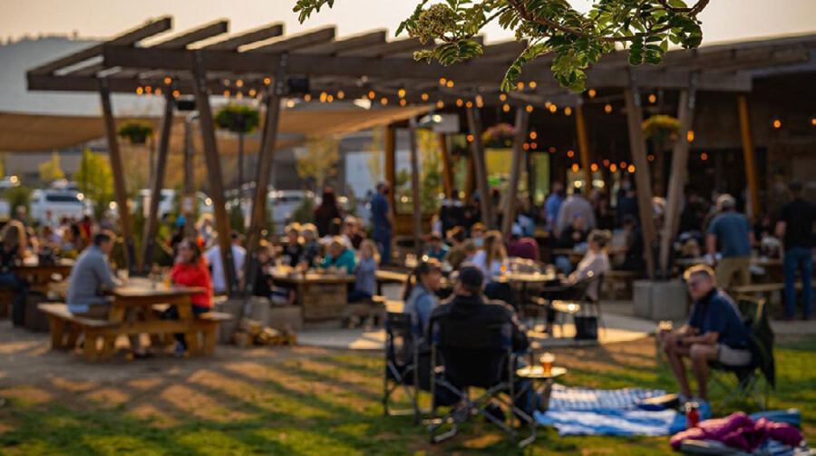 People gathered under string lights at an outdoor beer garden