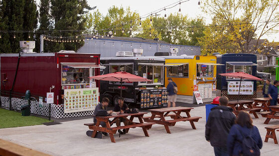 A cluster of food carts with picnic table seating