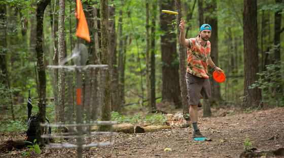 A disc golfer putting on a wooded course